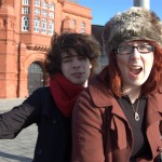 Tourists pose on a cannon near the Pierhead Building